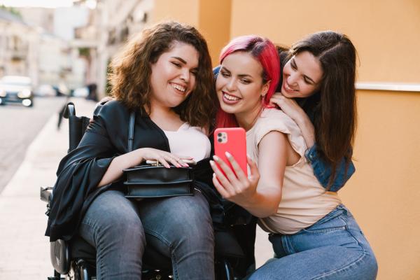 Three smiling young women taking a selfie in a street