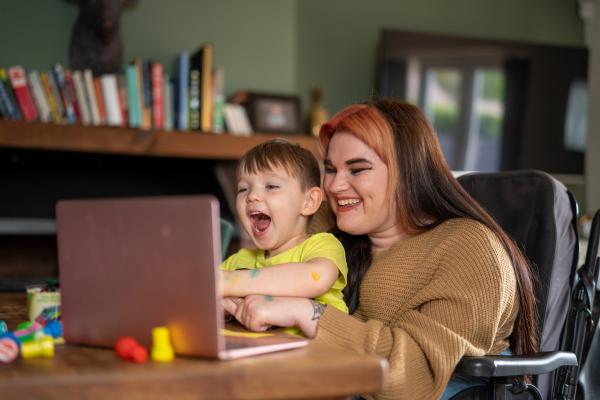Young woman with small child looking excited sitting at a laptop together.