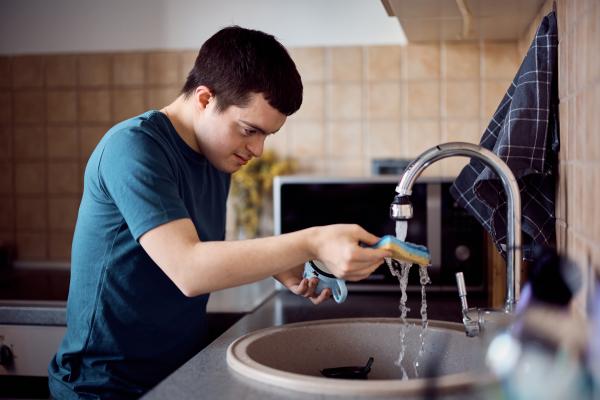 Young man washing his cup under a running tap