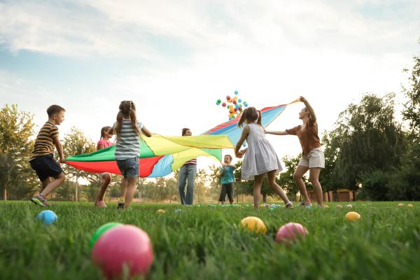 A group of children playing outside with colourful fabric and balls