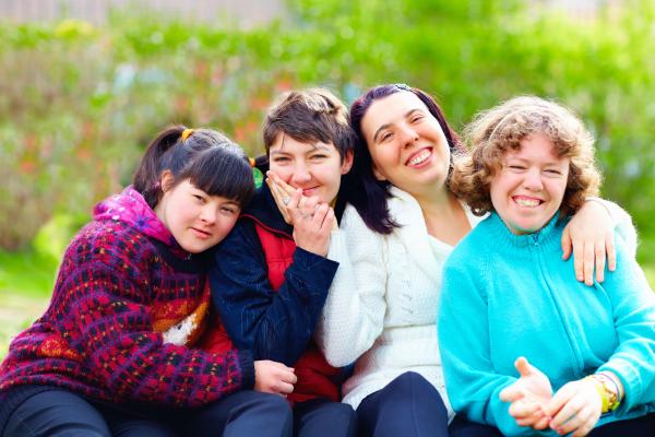 A group of 4 smiling young women, with their arms round each other