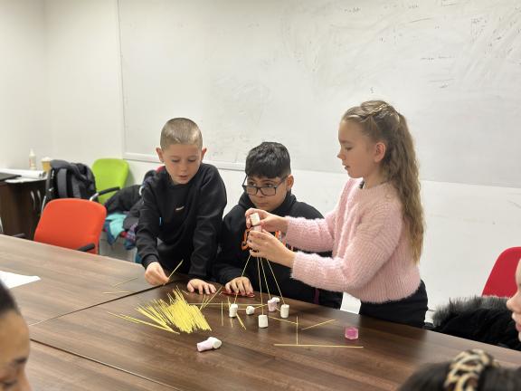 Three children building with sticks and marshmallows