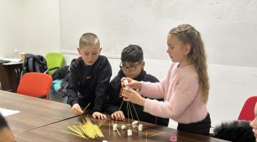 Three children building with sticks and marshmallows